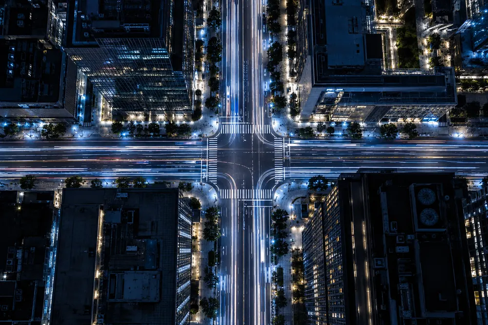 Aerial view of a city intersection at night with blue and white car light trails